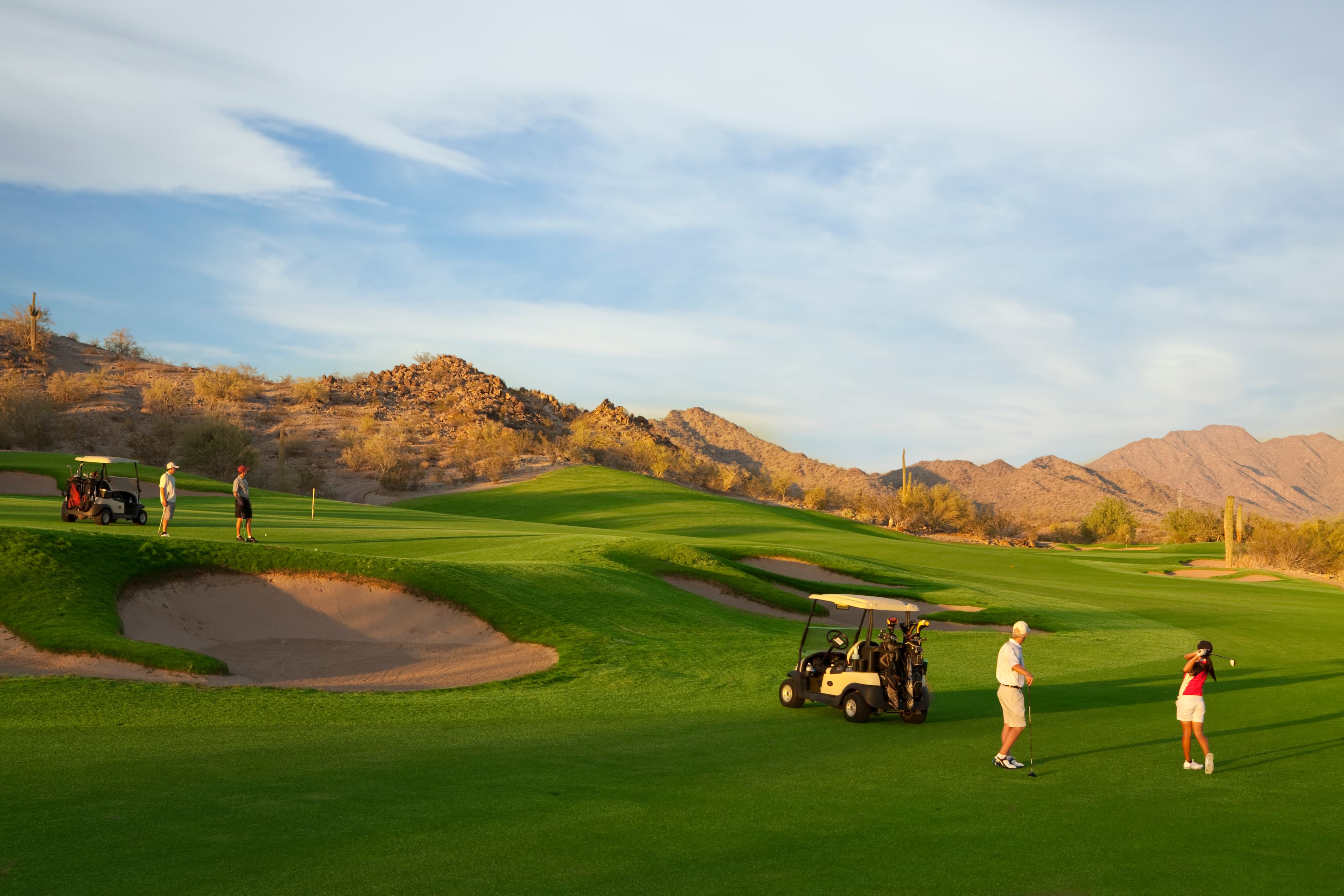 golf course with golfers, surrounded by mountains 