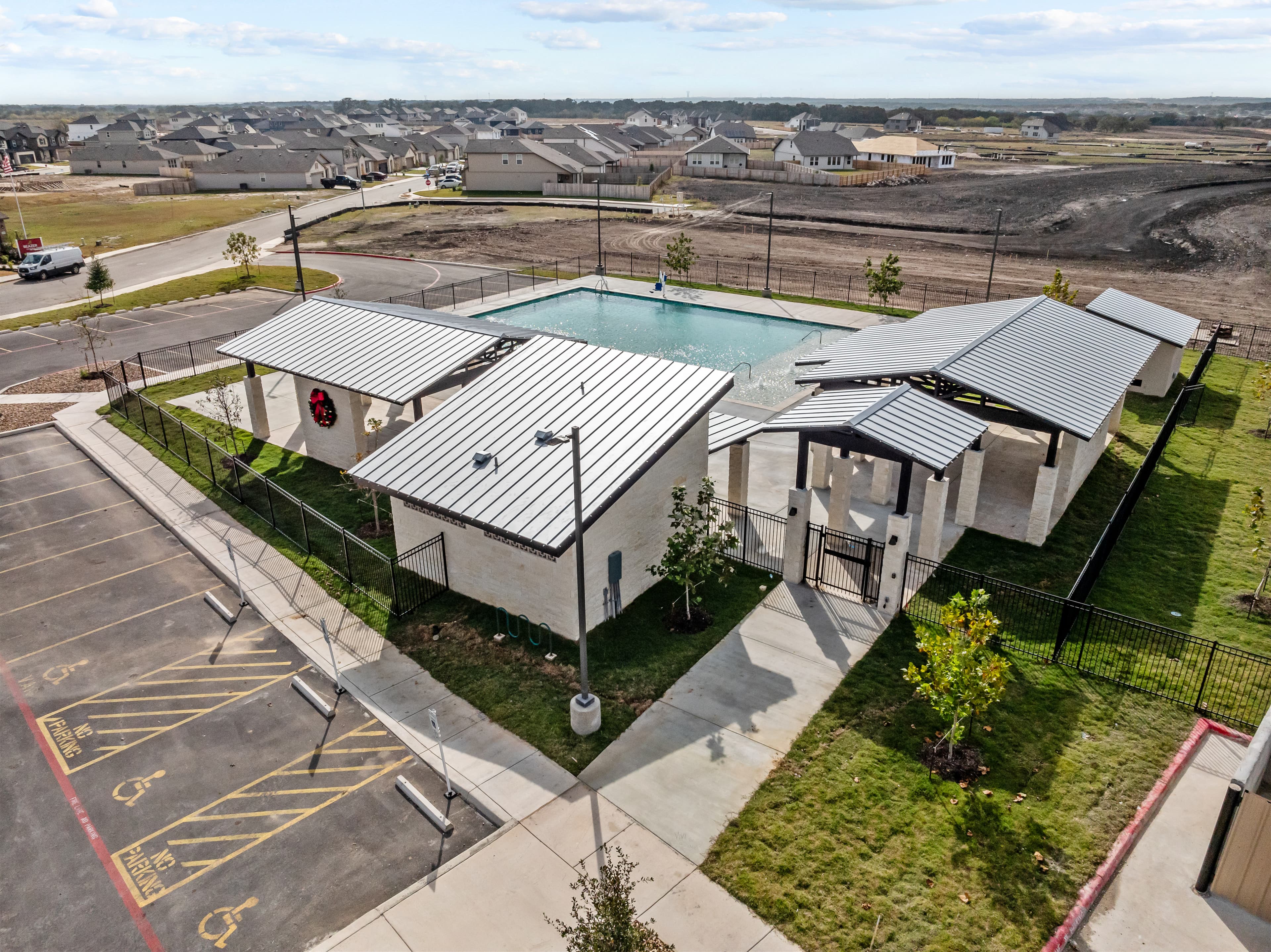 pool & amenity center with a black gate & grass