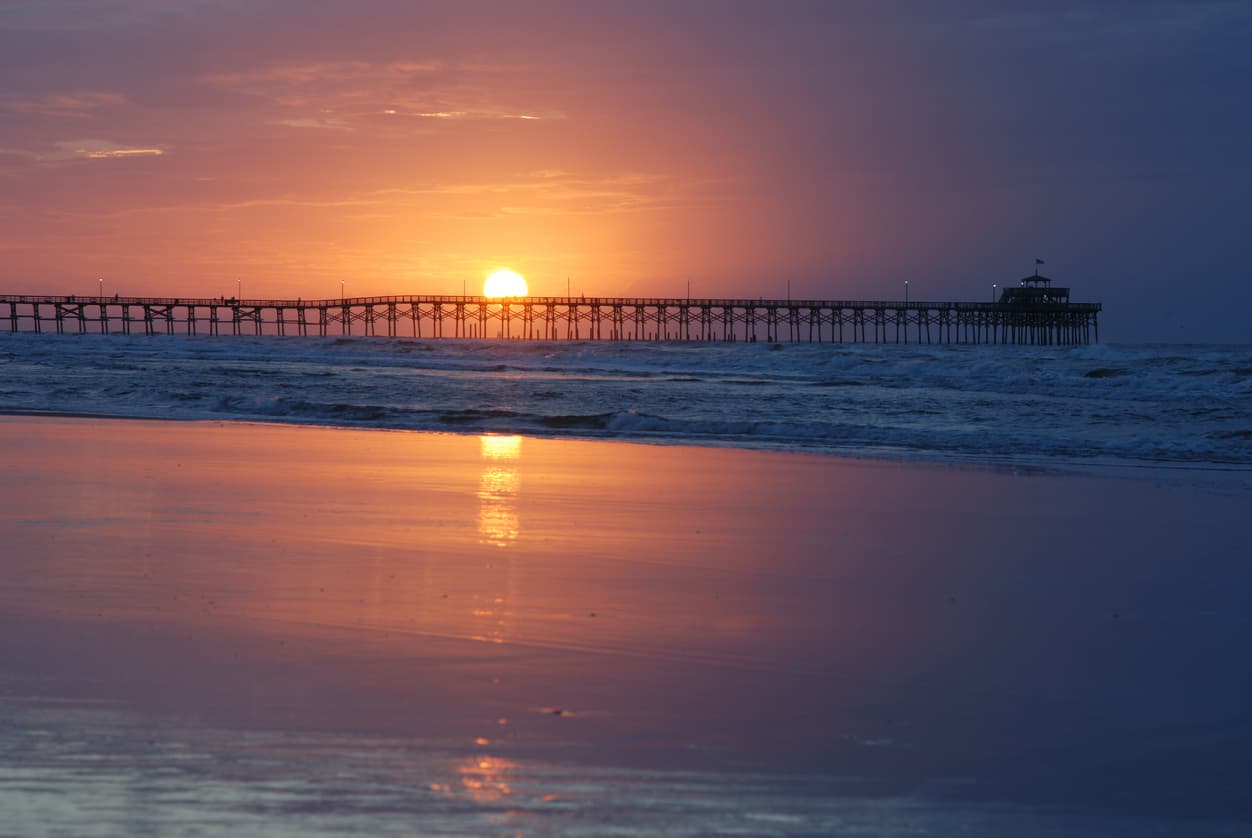 beach with a pier and the sunset