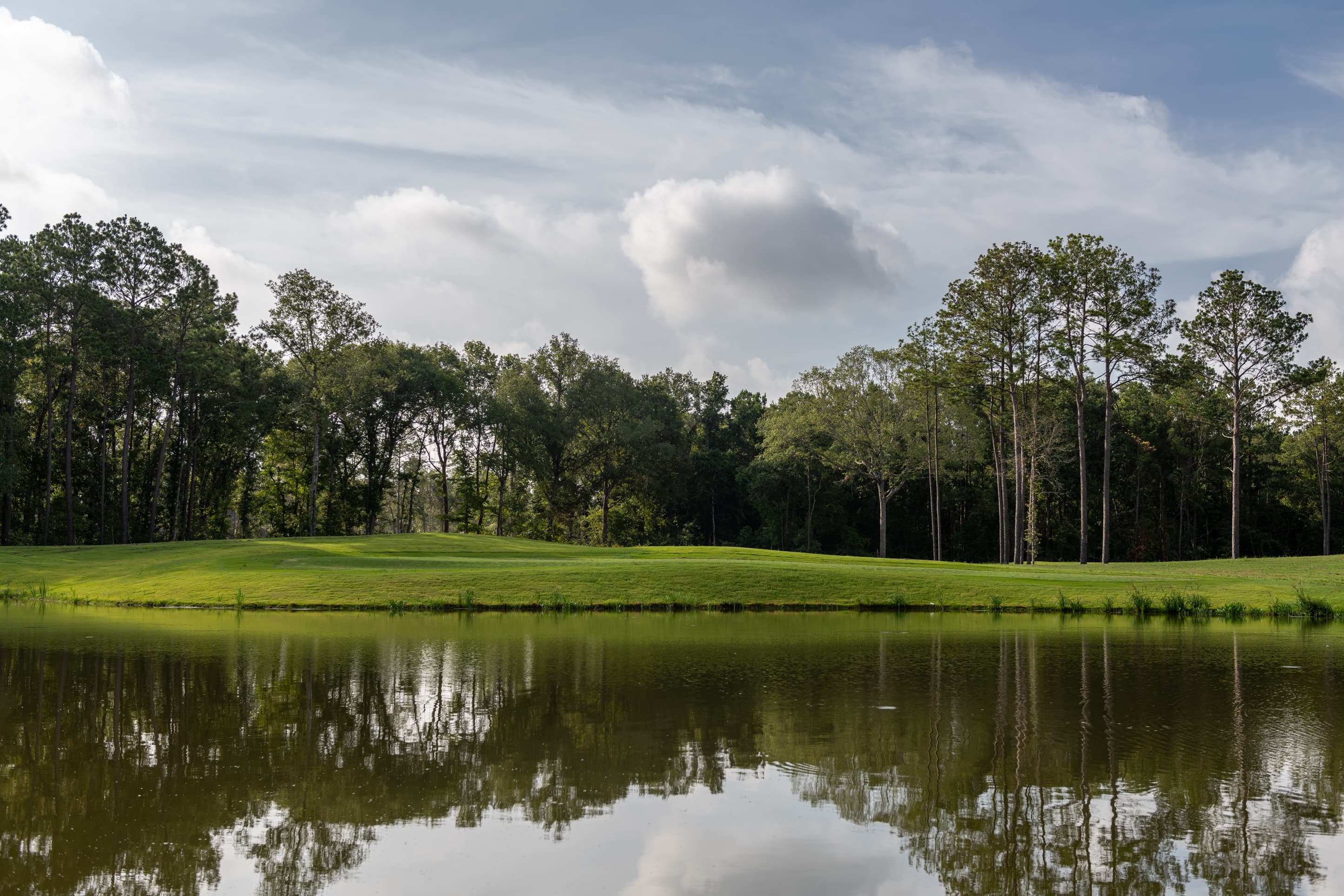 golf course next to water and wooded area