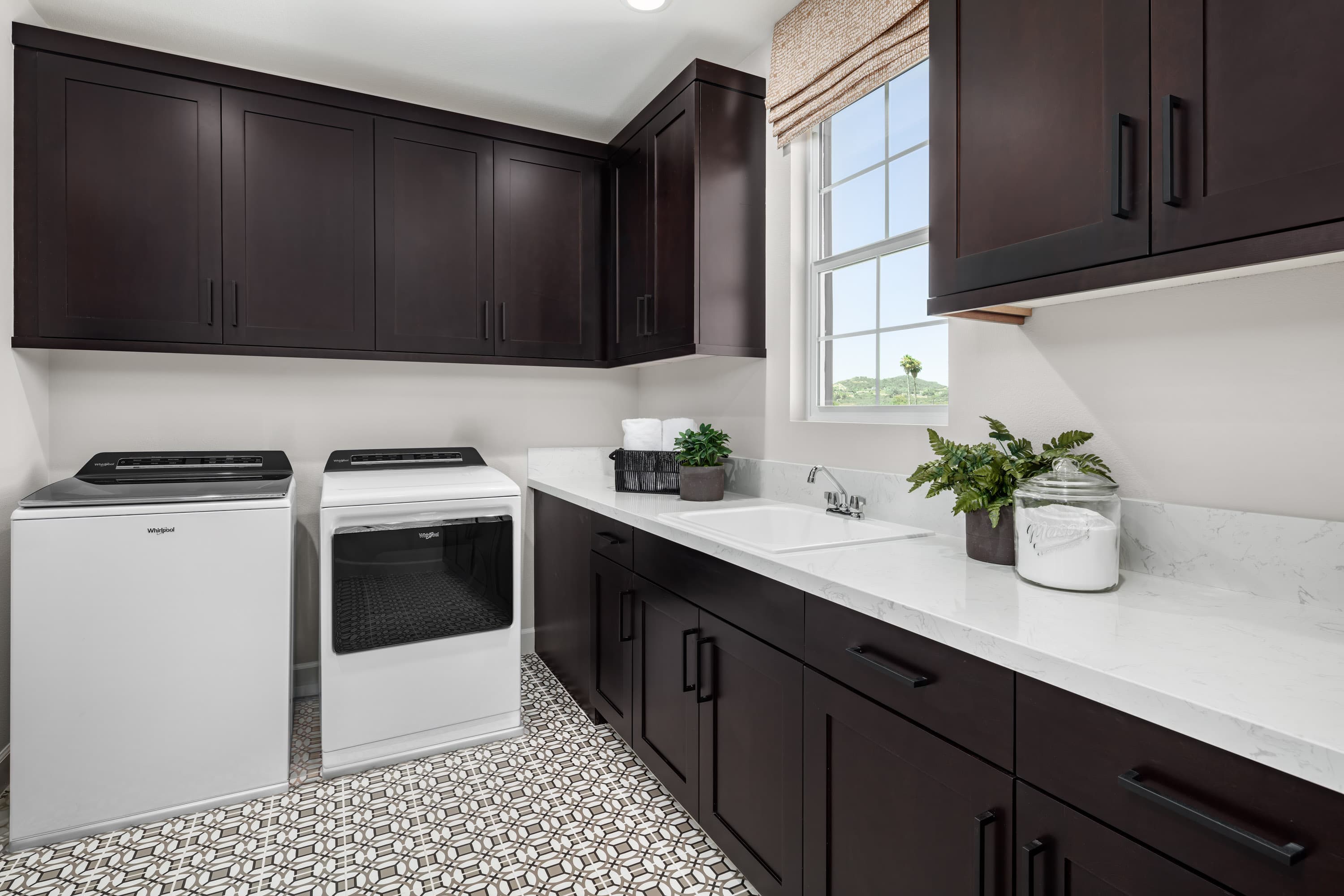 laundry room with tiled floors and dark cabinets