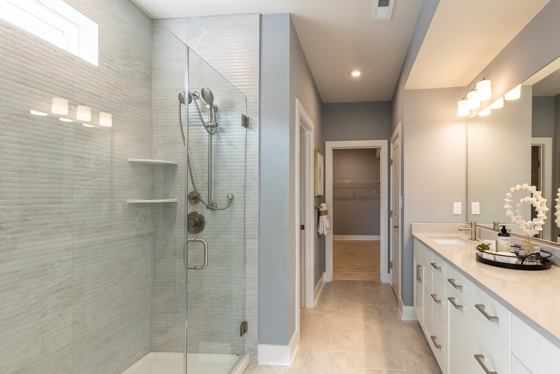 primary bath with dual vanities and a large shower