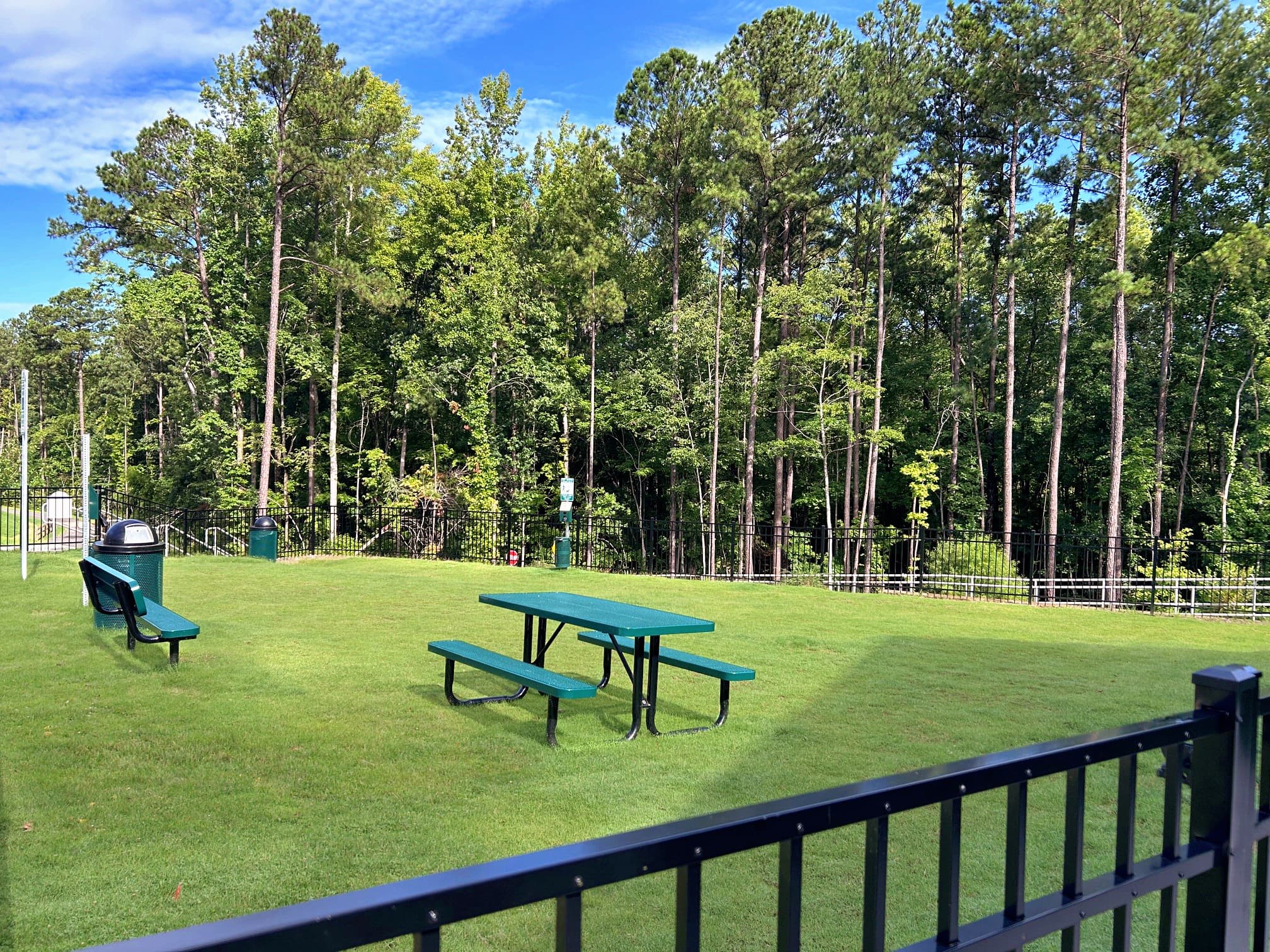 fenced-in dog park with a bench and a table