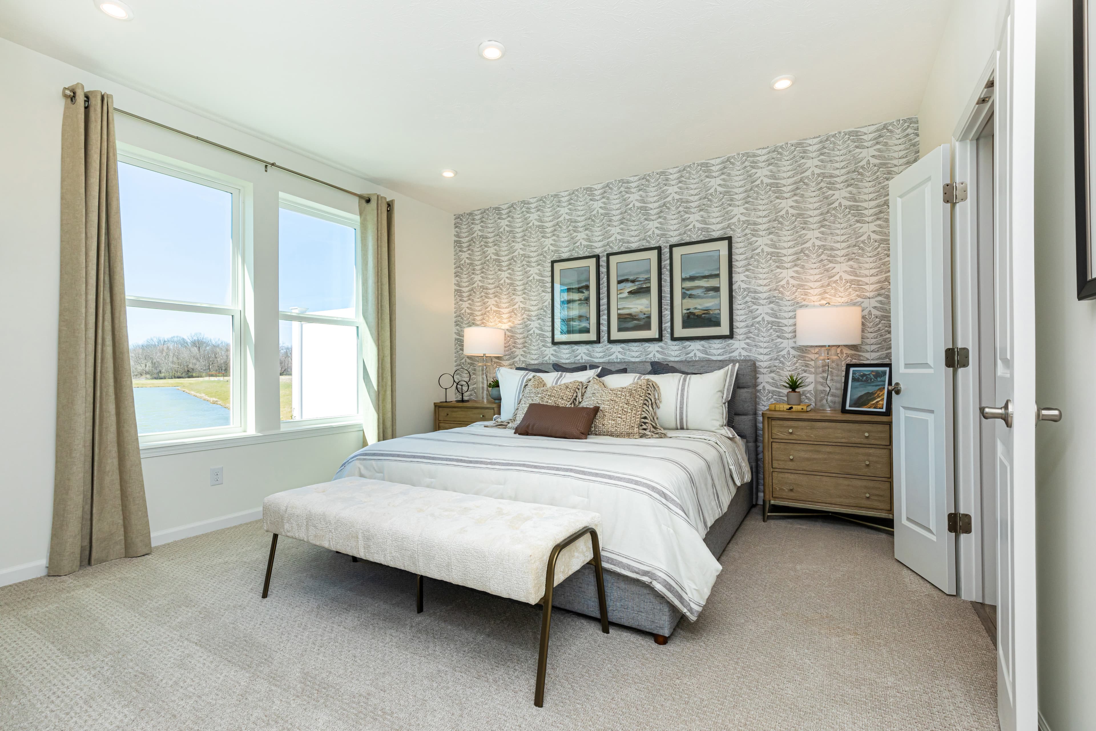 primary bedroom with wall paper and two windows 