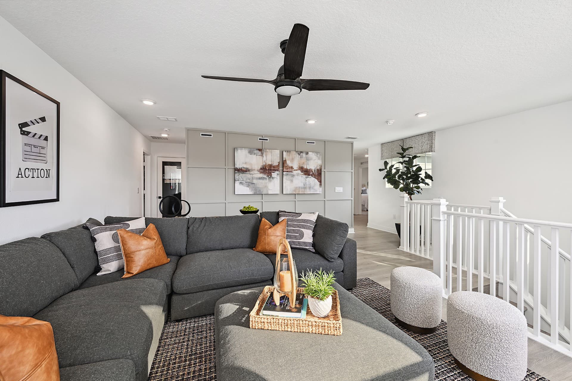 loft space with gray sectional and ceiling fan