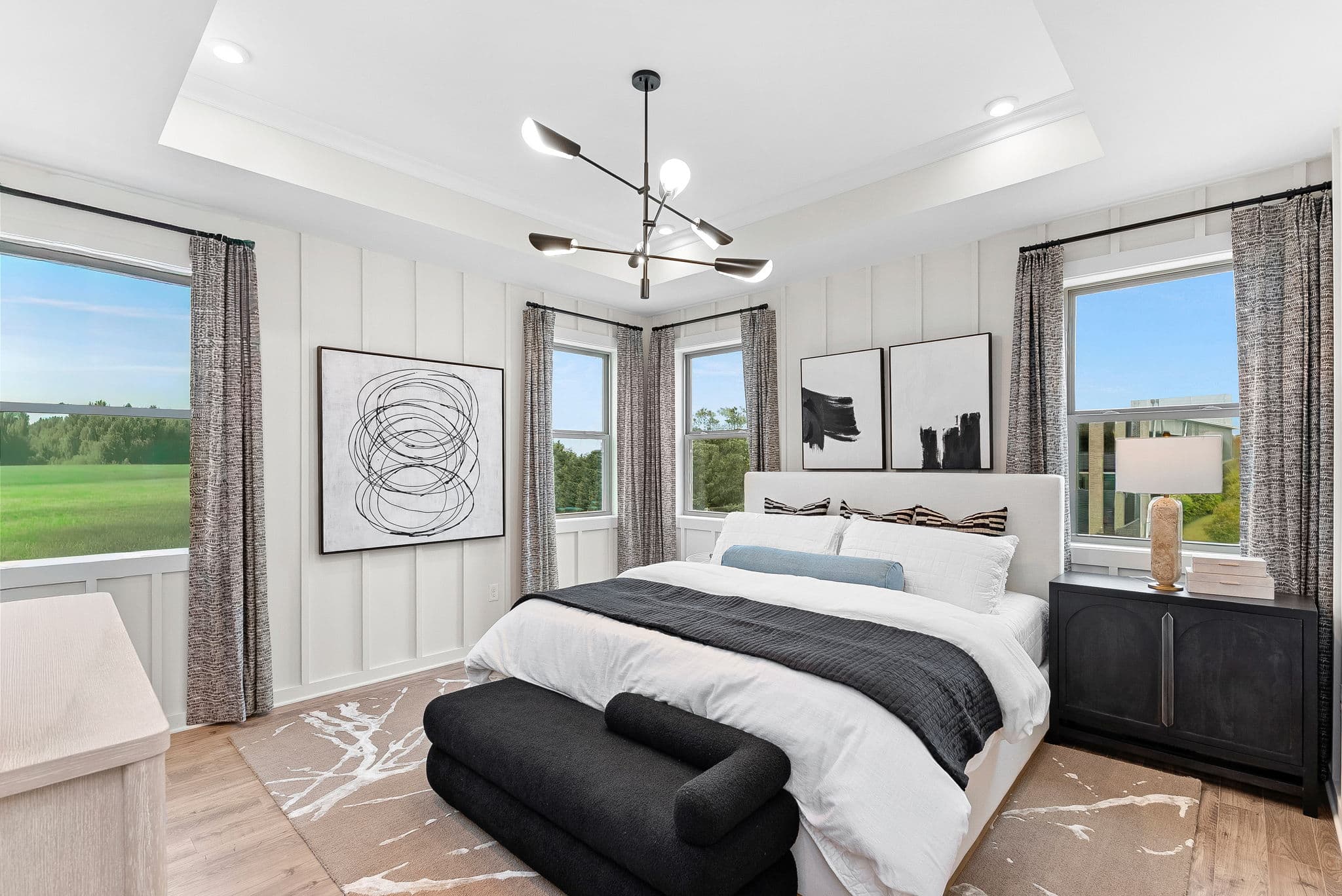 primary bedroom with multiple windows and a nightstand
